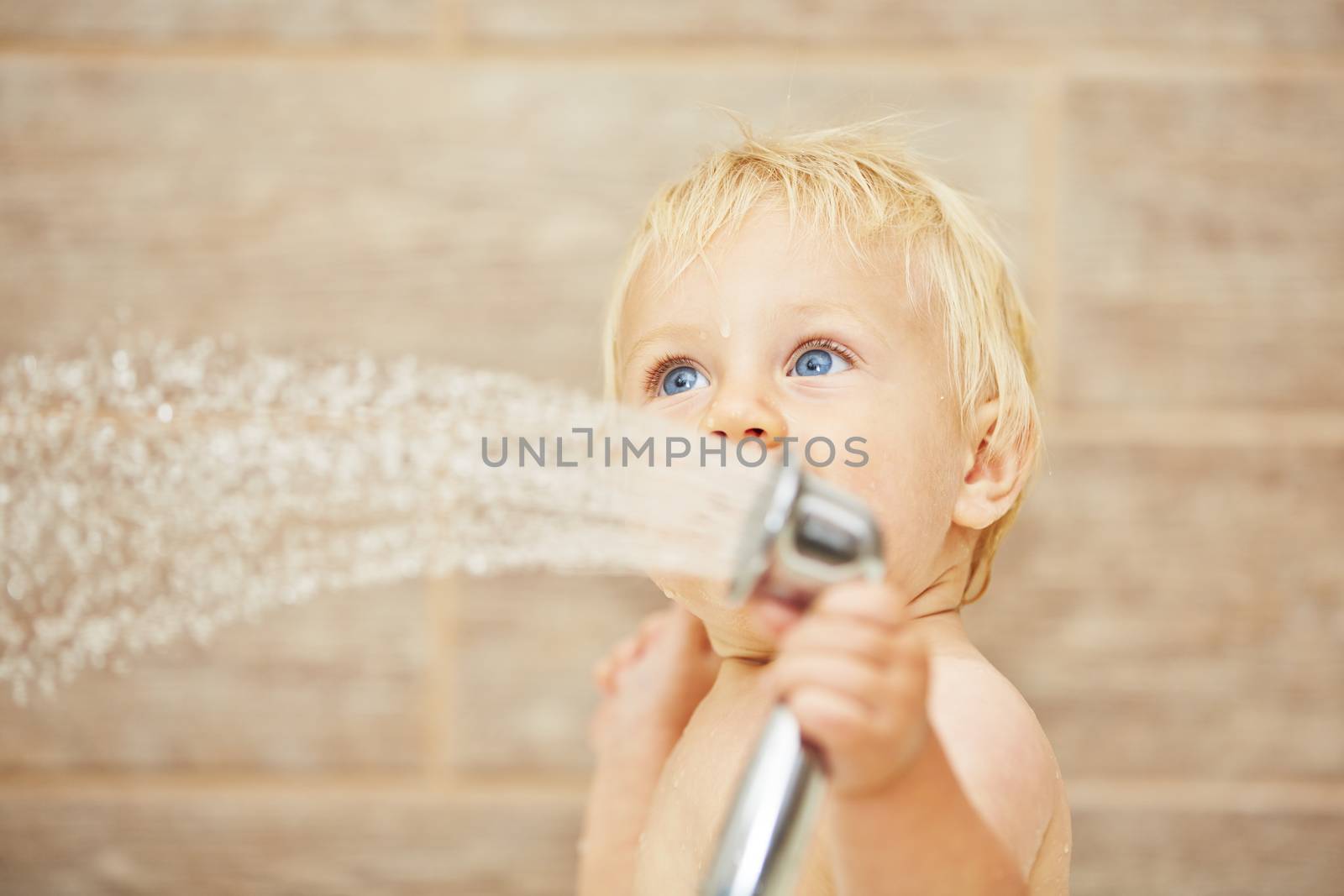 Blond baby taking shower in the bathroom 