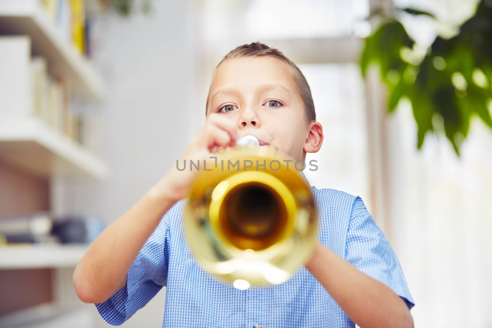 Little boy is playing the trumpet at home 