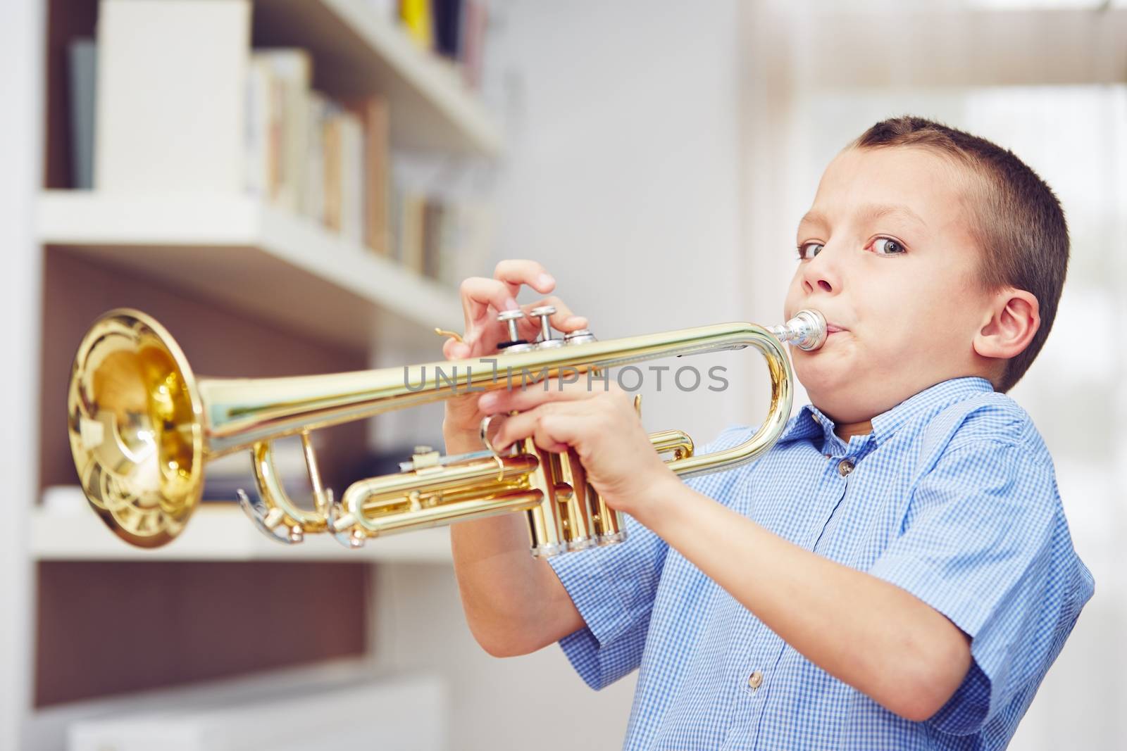Little boy is playing the trumpet at home 