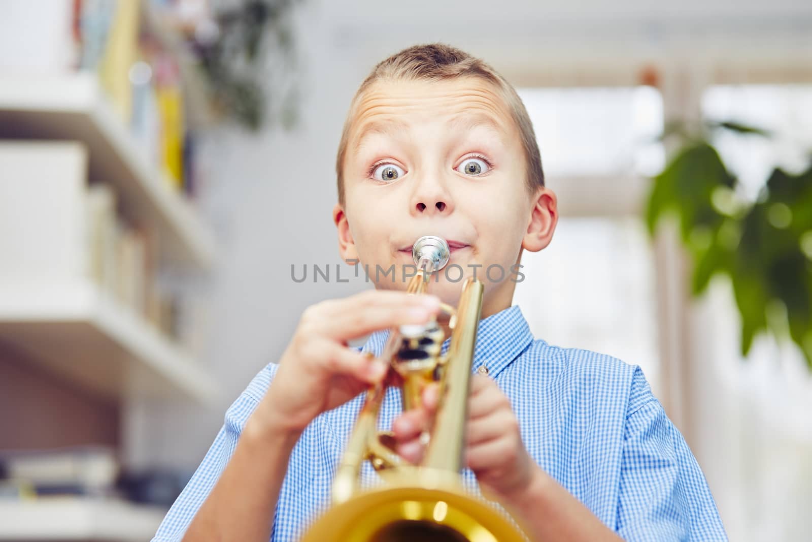 Little boy is playing the trumpet at home 