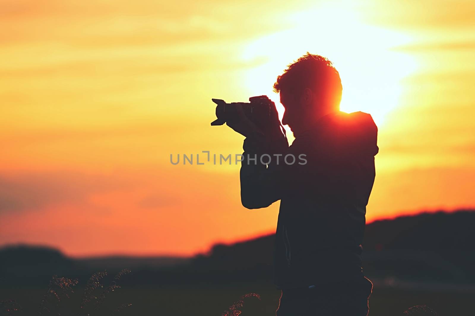 Silhouette of the young photographer at the sunset.