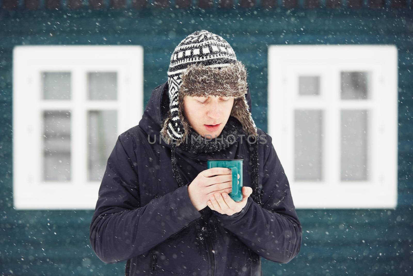 Portrait of young man outdoors in winter under snowstorm