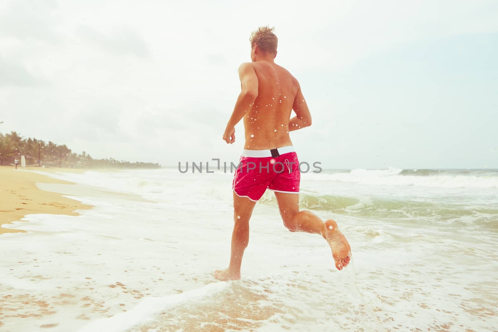 Young man is running on the beach