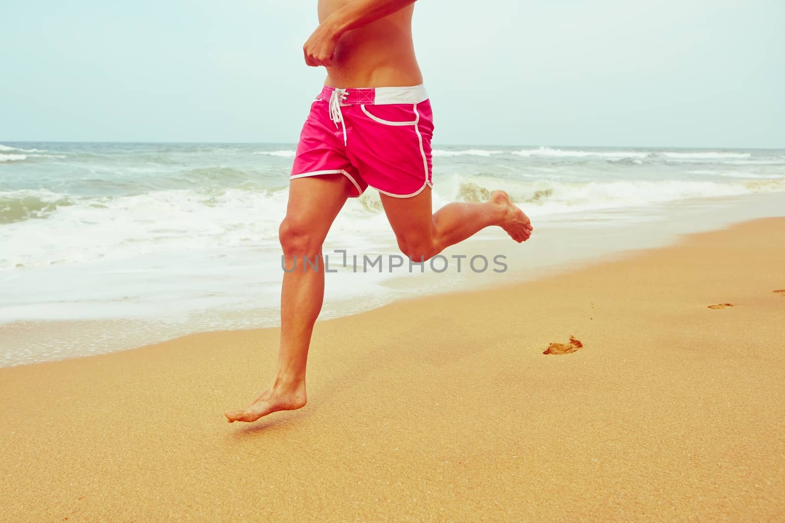 Young man is running on the beach