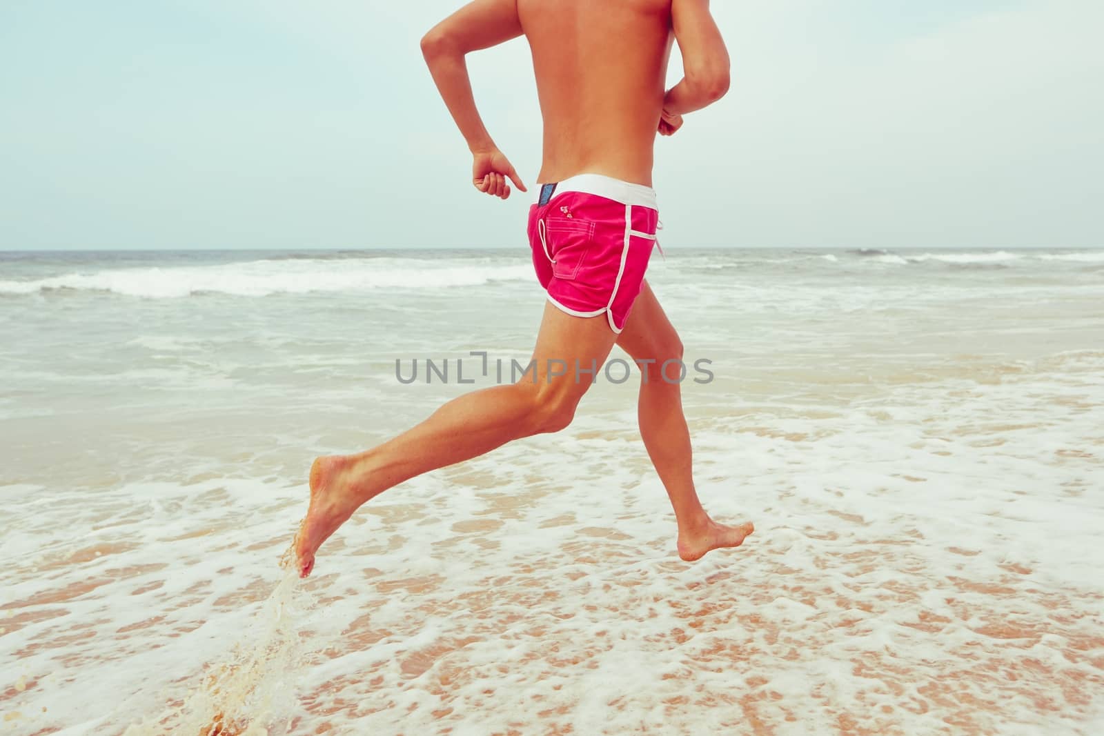 Young man is running on the beach