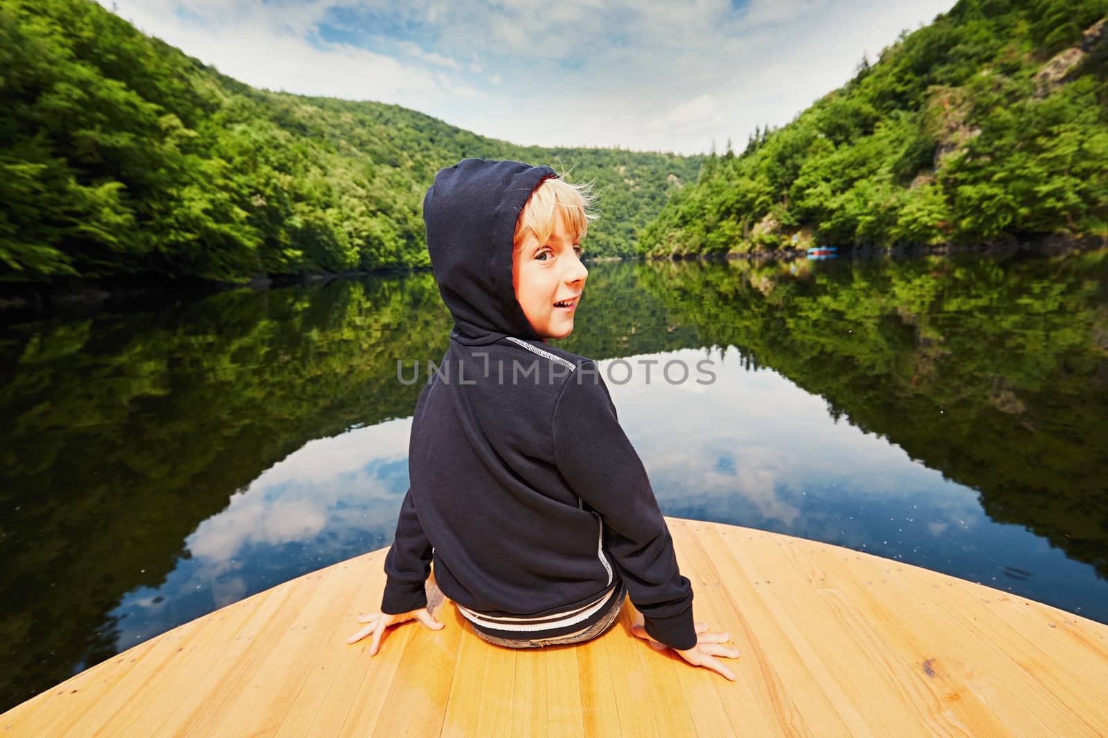 Little traveler on the river. Boy is sitting on the boat.