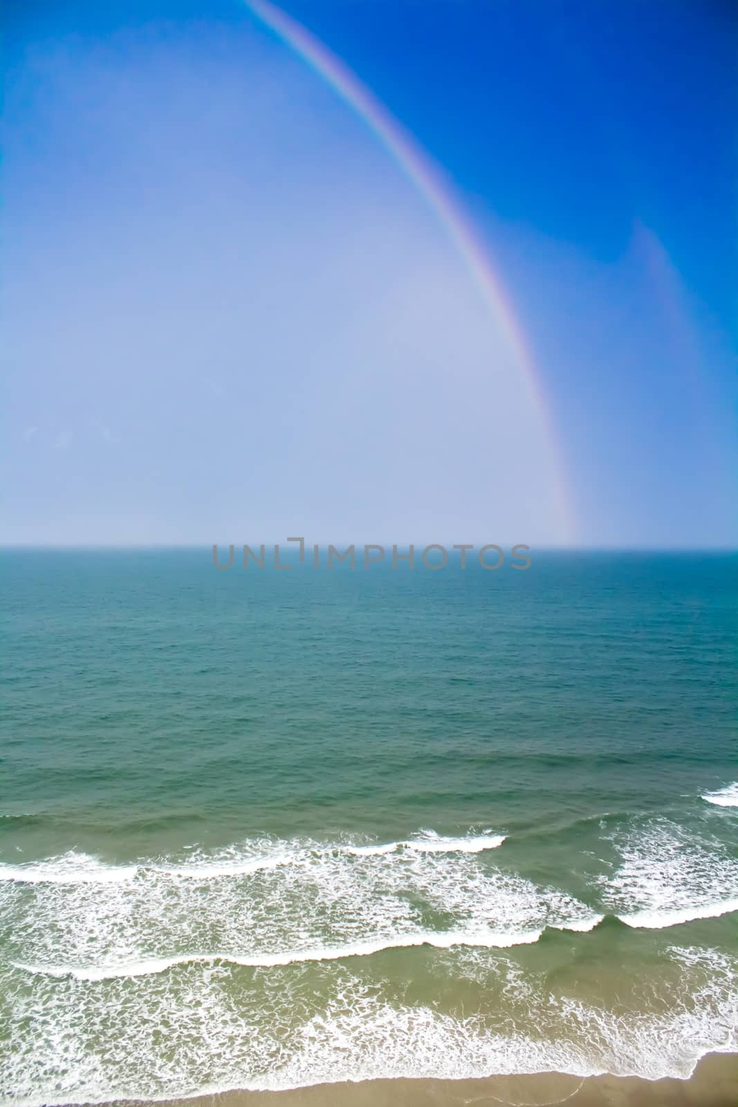 Colorful Rainbow over the Beach Shoreline by enterlinedesign