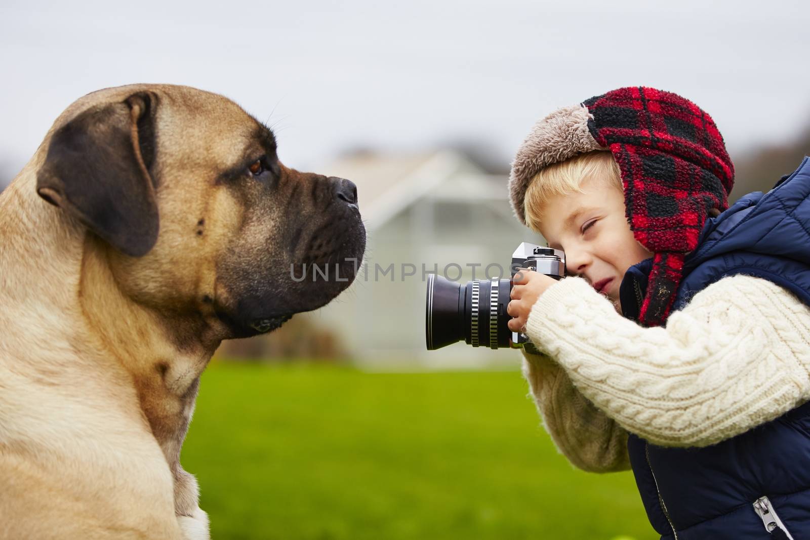 Little boy with camera is shooting his dog