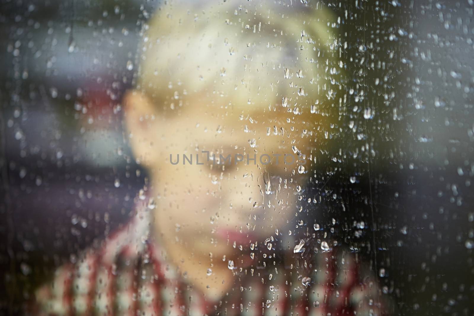 Little boy behind the window in the rain - selective focus