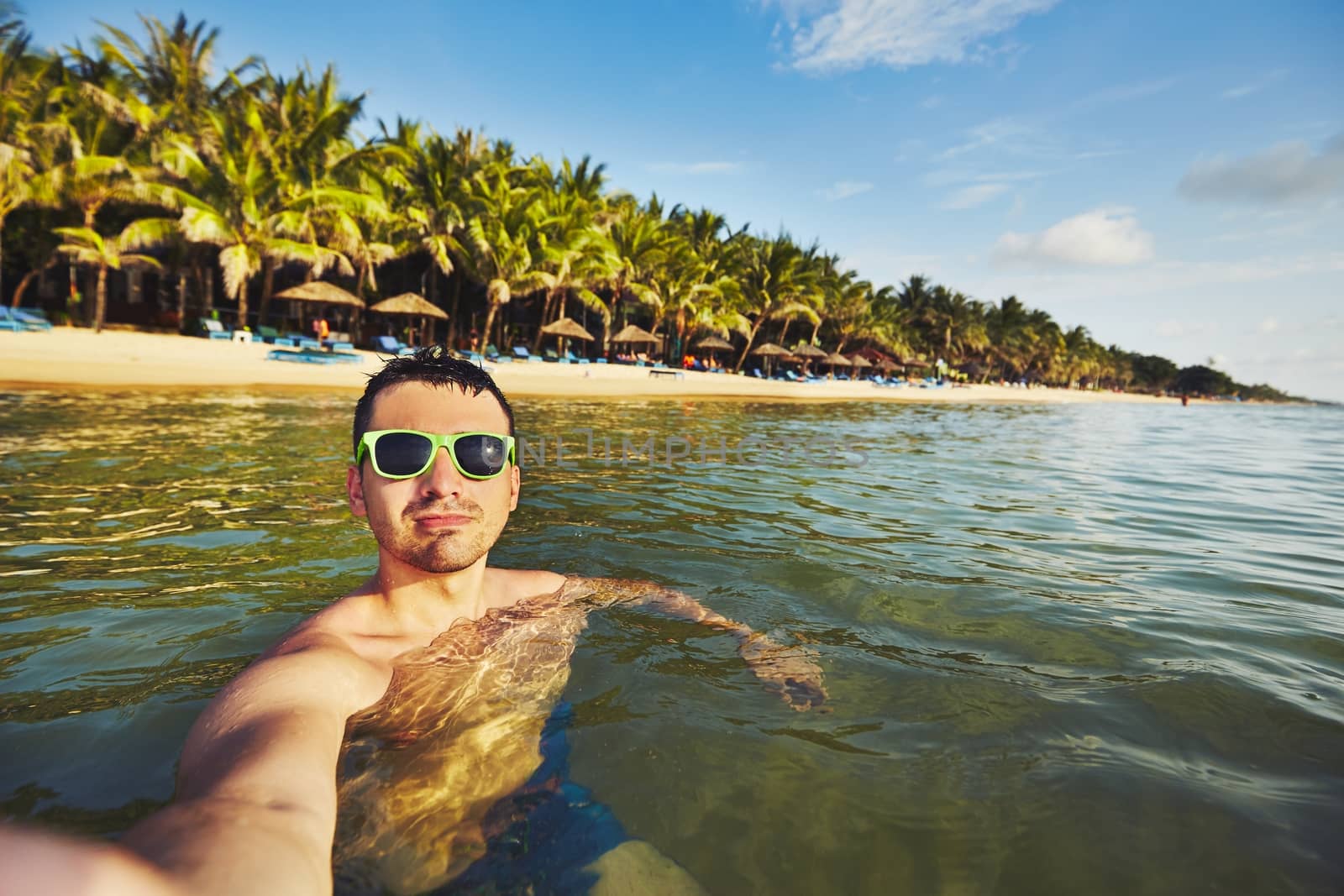 Young man on vacation taking selfie in the sea.