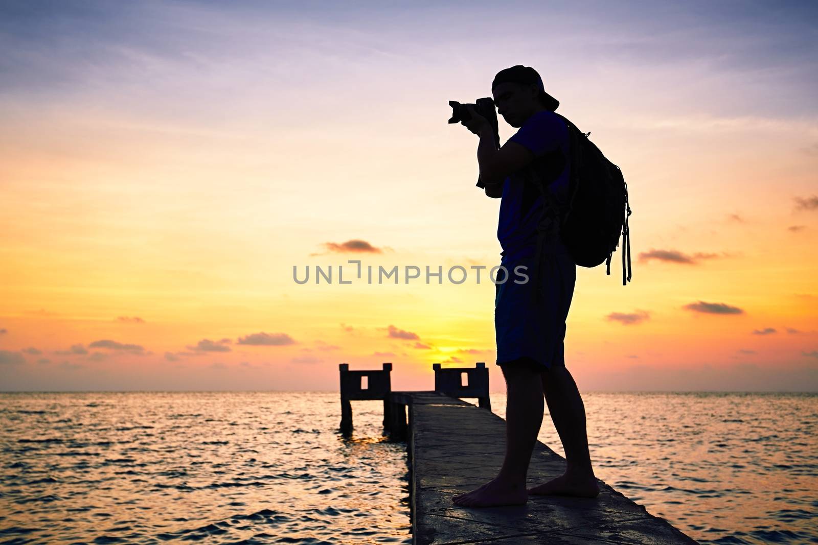 Young photographer is taking photos at the sunset.
