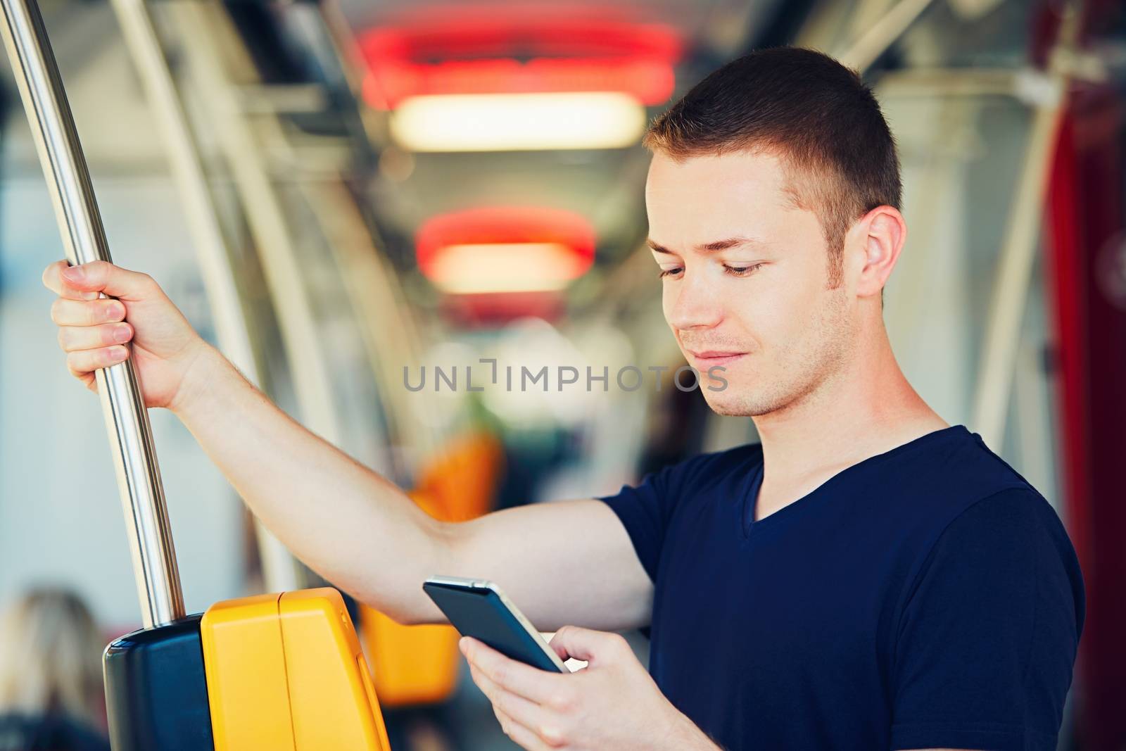 Everyday life and commuting to work by bus (tram). Handsome man is paying transport ticket with mobile phone. 