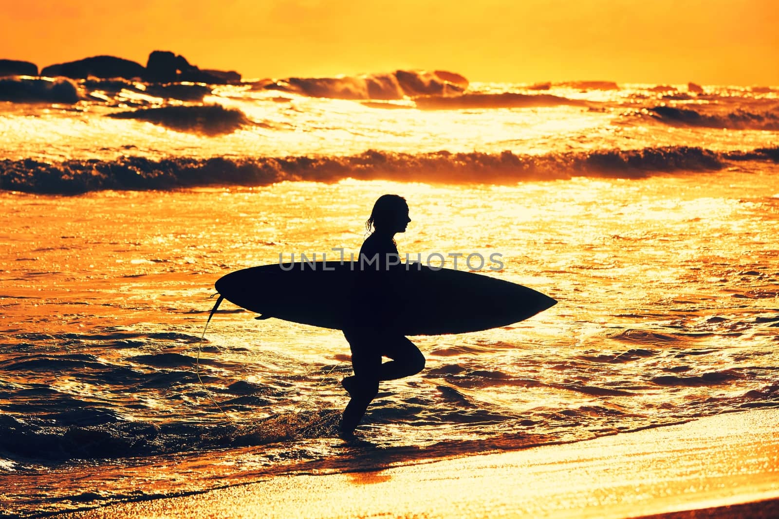 Silhouette of the beautiful surfer girl is enjoying vacation on the tropical beach. Young woman with surfboard at golden sunset. Sri Lanka. - back lit