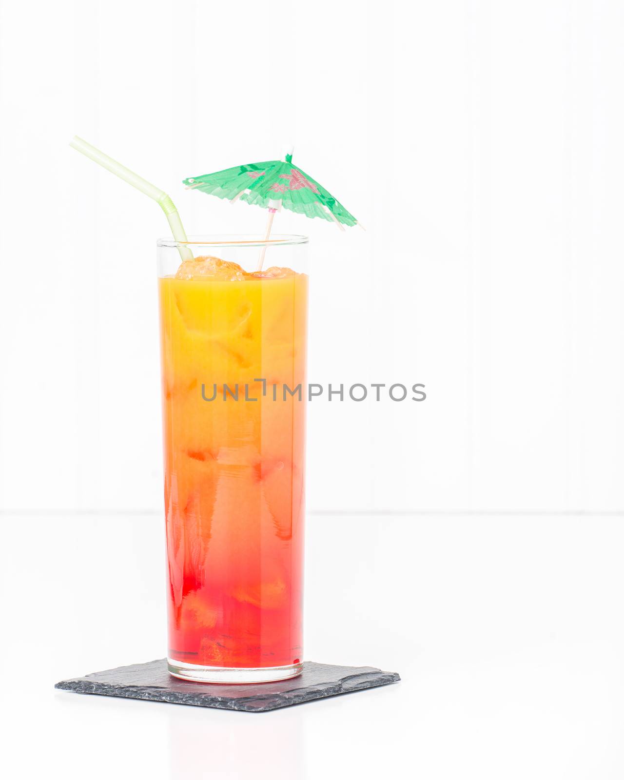 Tropical cocktail known as a tequila sunrise in a tall glass with ice.