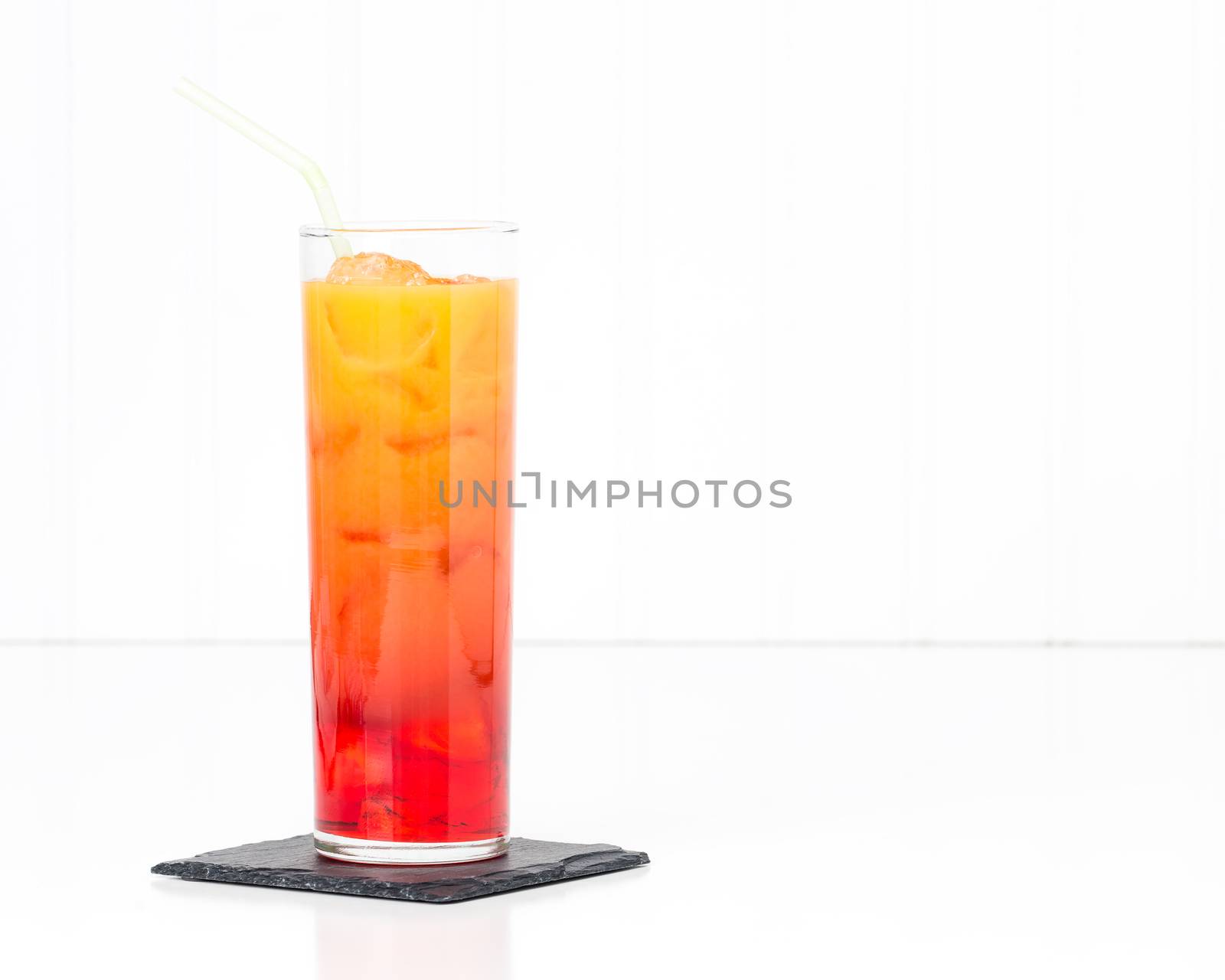 Tropical cocktail known as a tequila sunrise in a tall glass.