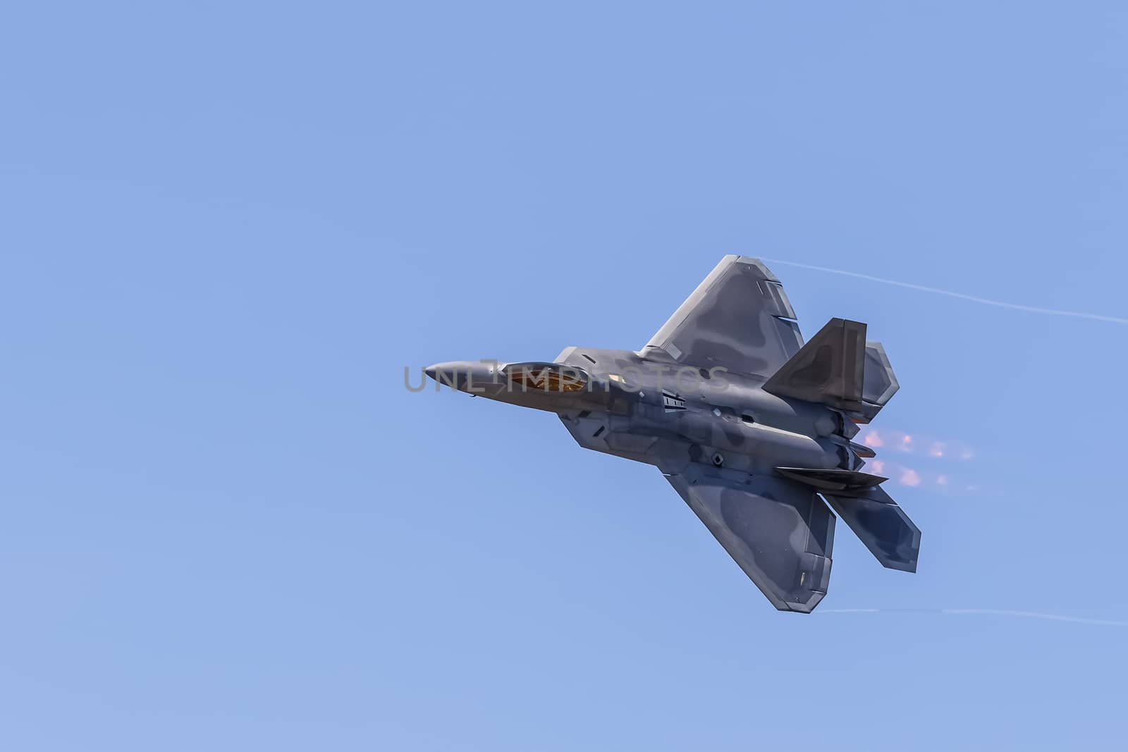 F-22 Raptor in flight with vapor clouds along the leading edges