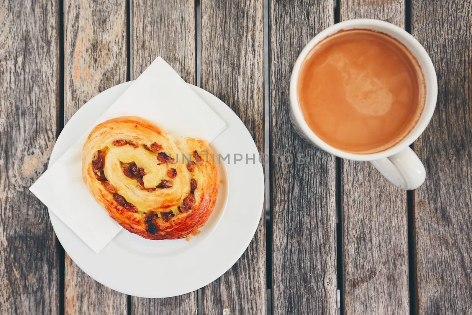 Morning coffee with with sweet pastries. Top view of snack and cup of the hot drink on wooden desk. 