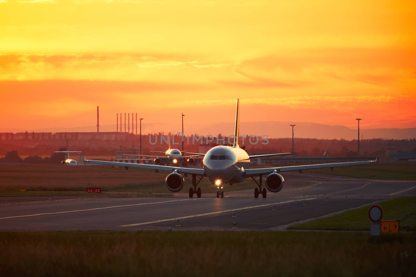 Airport traffic at the golden sunset. Airplanes are taxiing to the runway for take off.