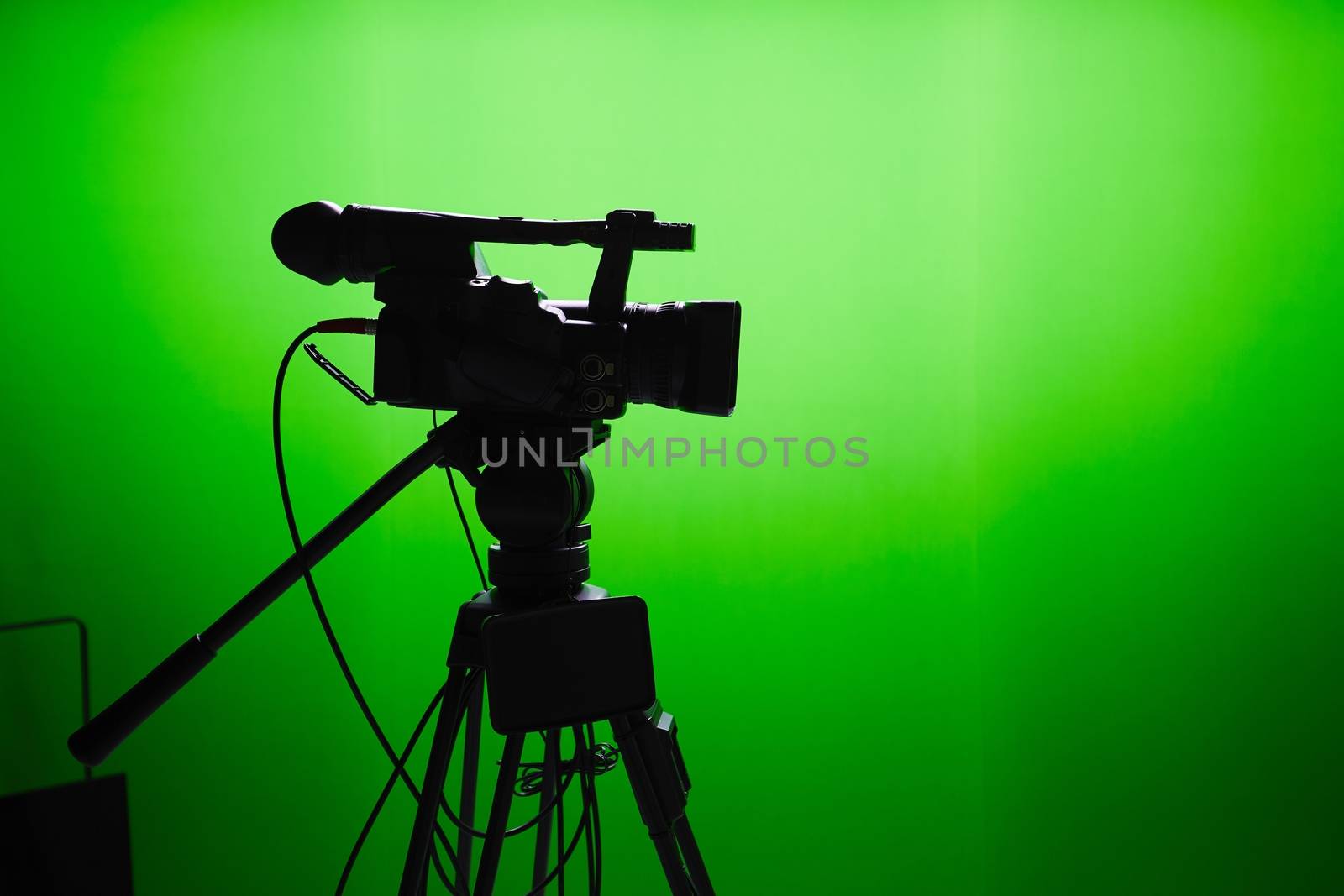 Silhouette of digital video camera in front of the green screen