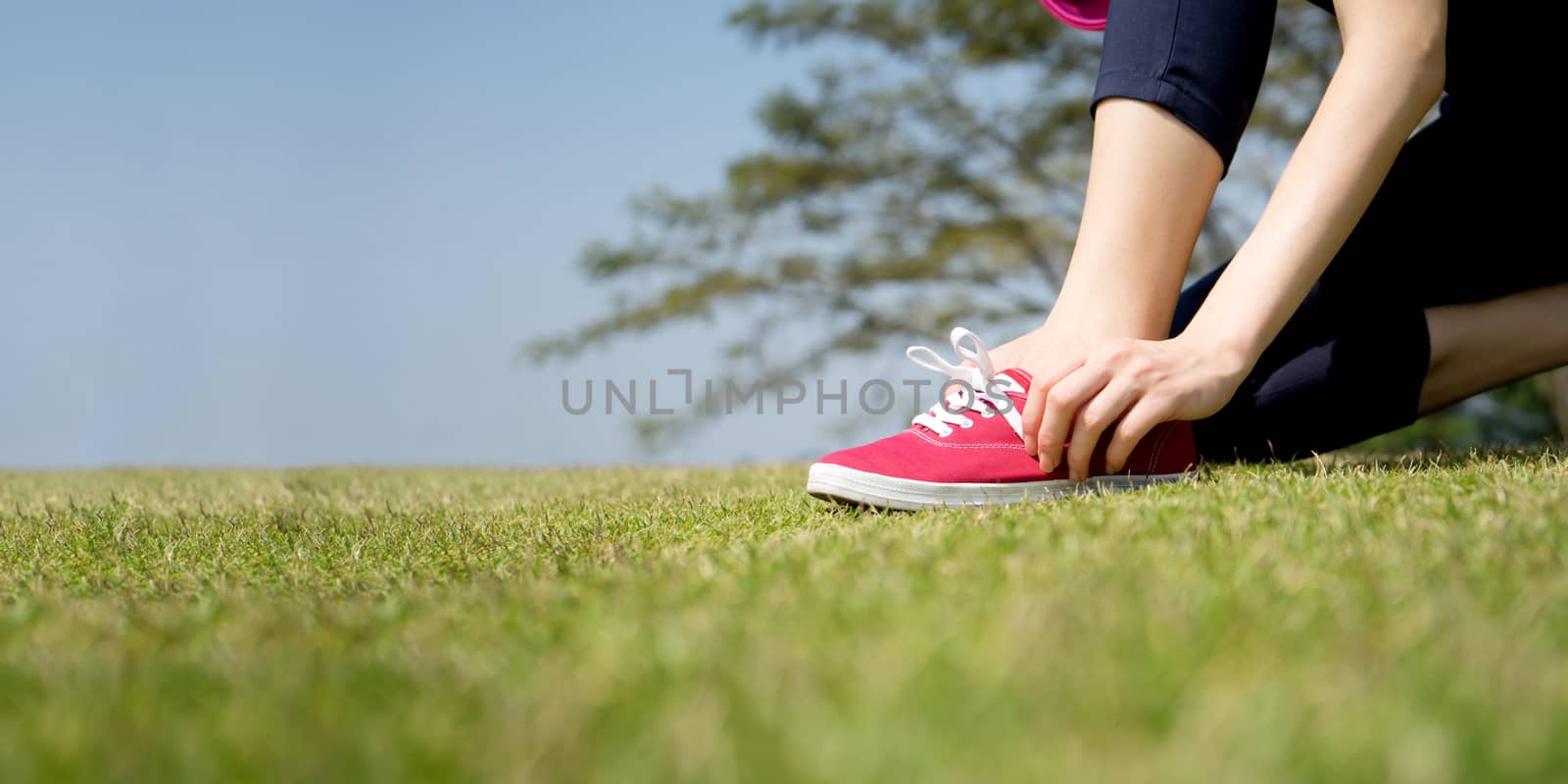 Running shoes - closeup of woman tying shoe laces on her barefoot running shoes. Female sport fitness runner getting ready for jogging outdoors.