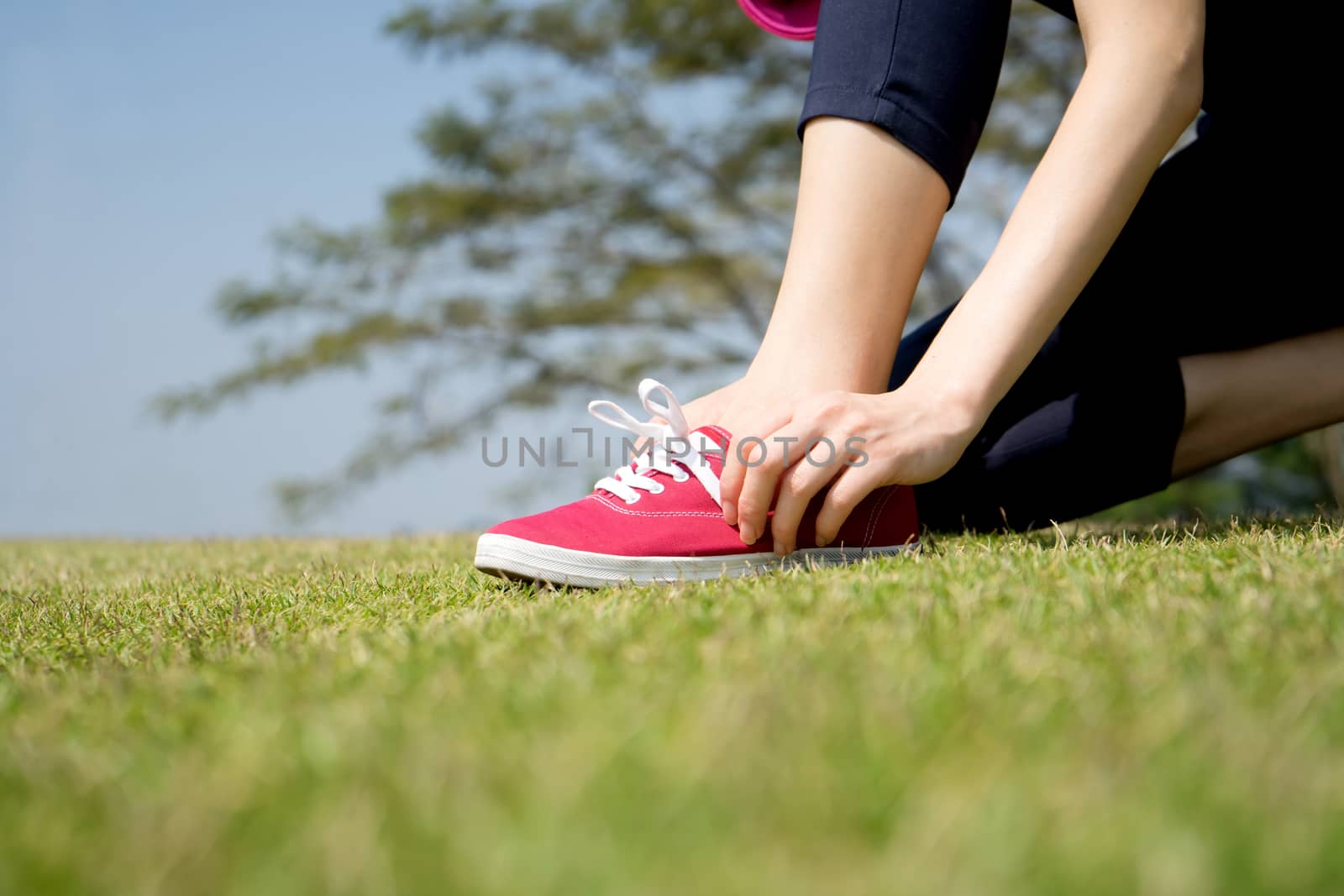 Running shoes - closeup of woman tying shoe laces on her barefoo by ekachailo