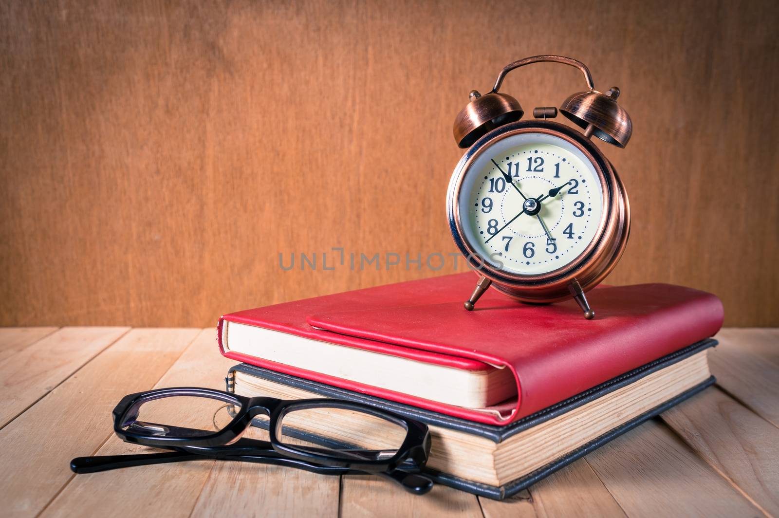 Retro alarm clock and book with glasses.