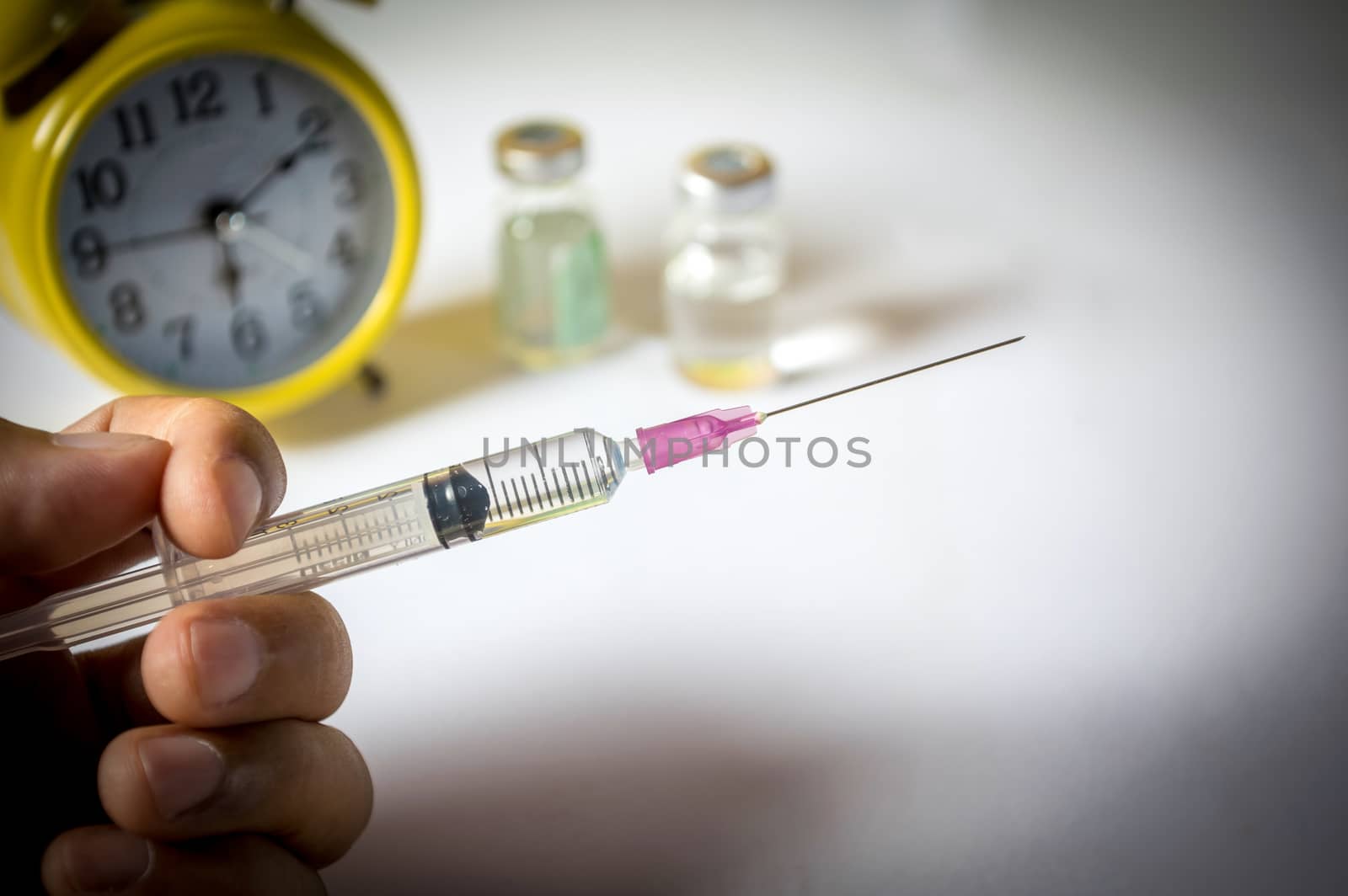 Hand holding syringe with clock.