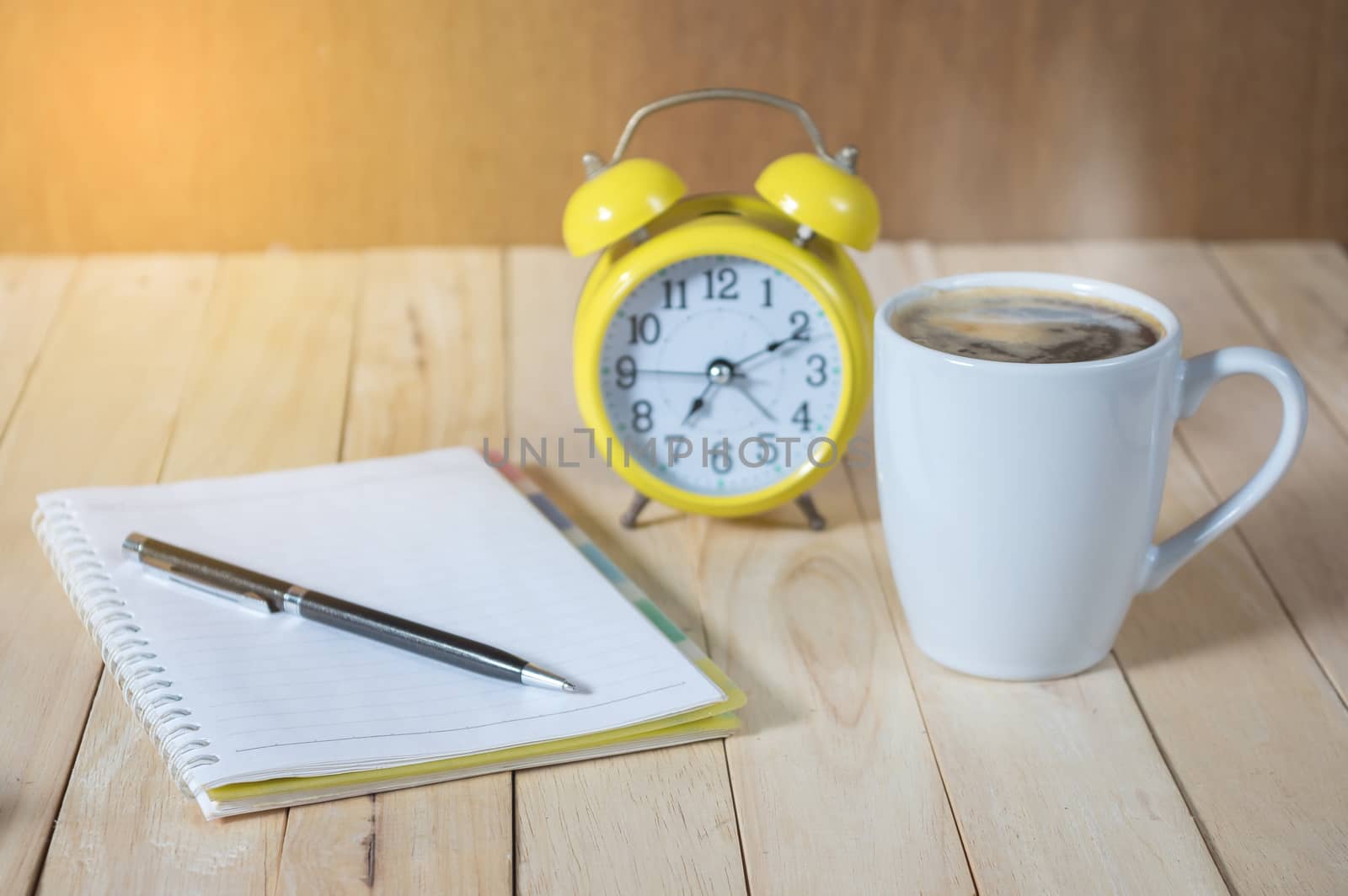 A cup of coffee on the table with calculator and clock.