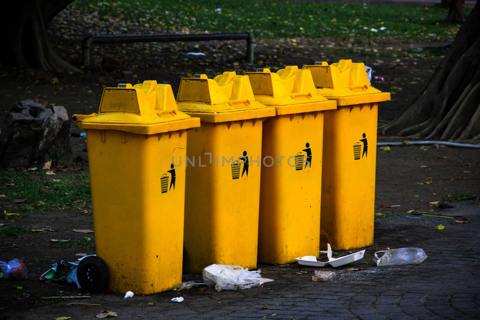 Garbage bins and pile of garbage on floor in park