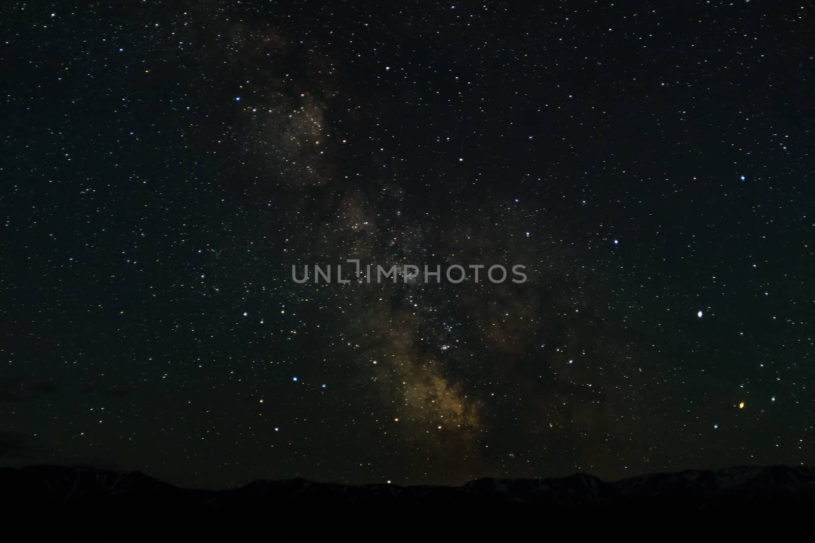 Night mountain landscape with snowy mountain peaks and edges night sky with many stars and milky way on background