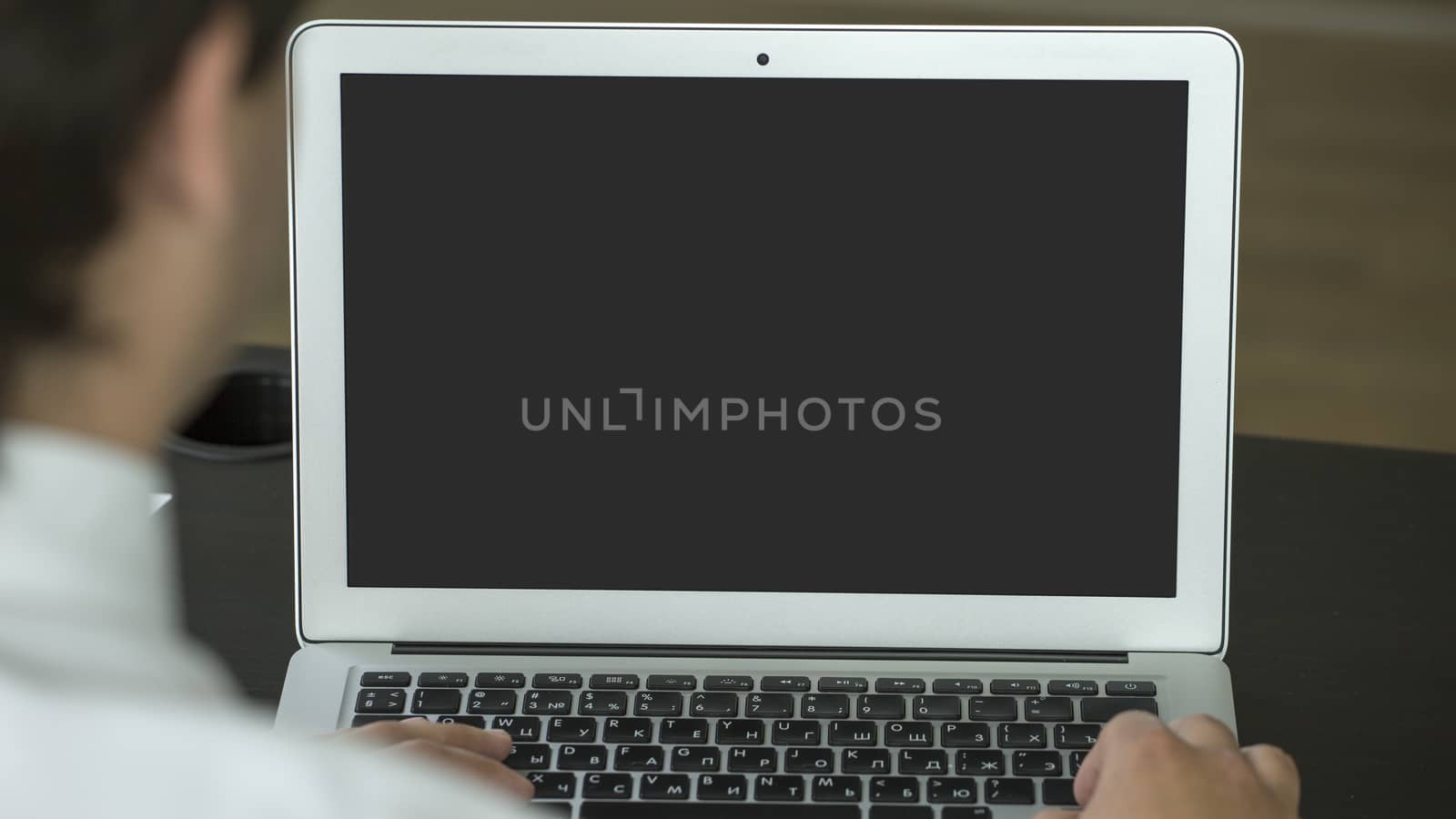 Closeup of businessman typing on laptop with blank screen. Mock up.
