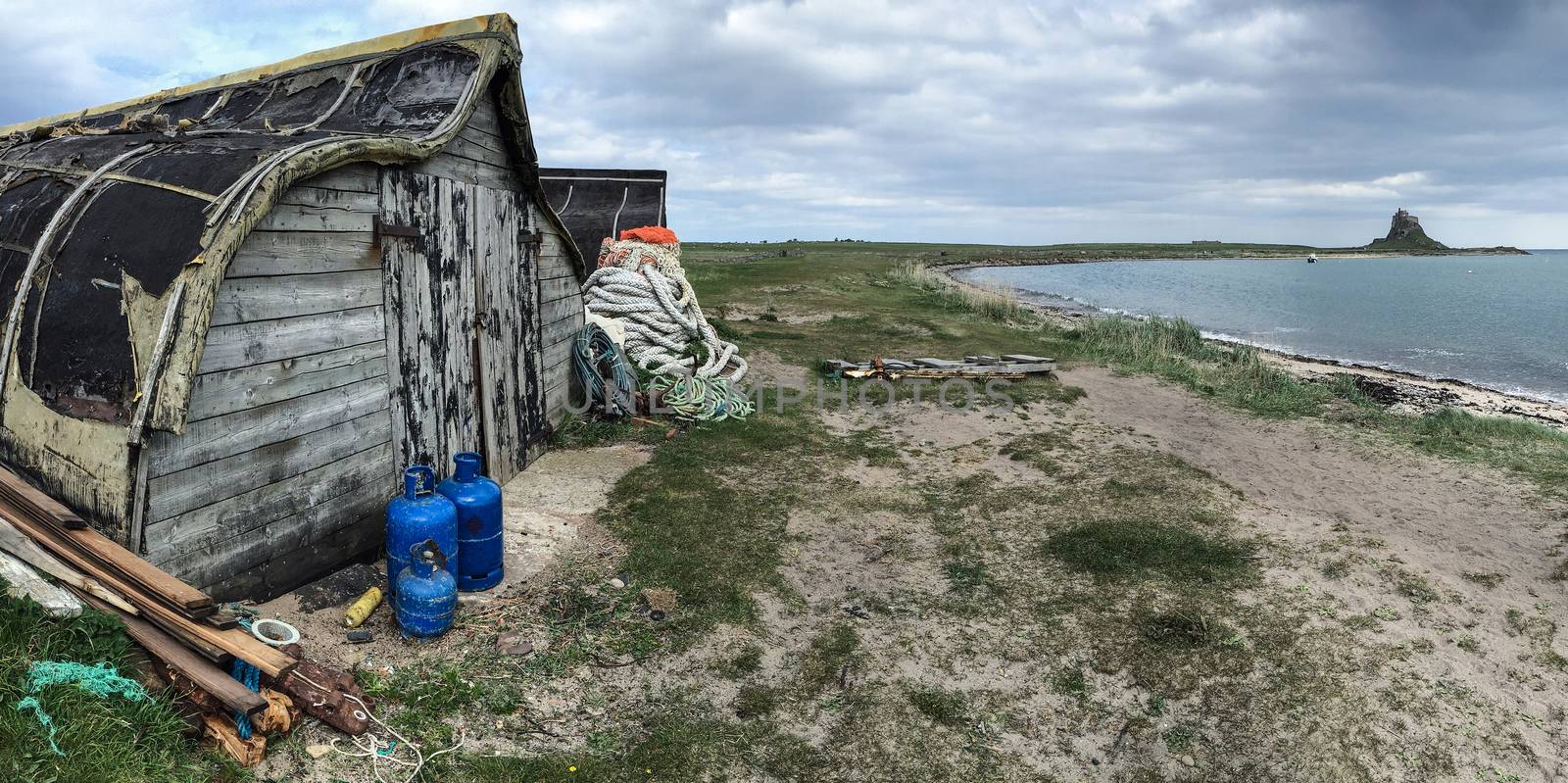 Old boatsheds on Holy Island with Lindisfarne Castle in the distance. Northumberland - England