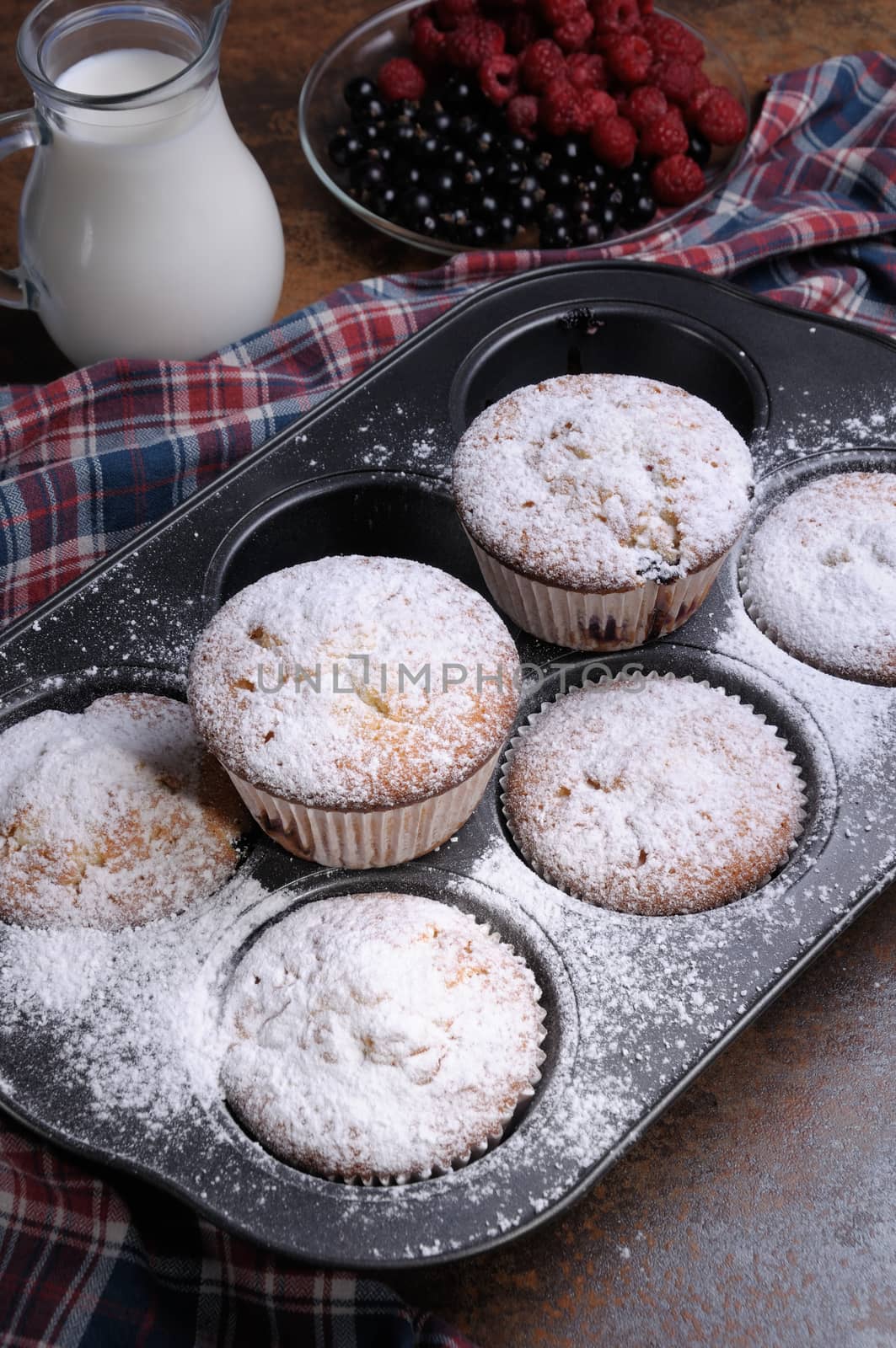 Muffins   sugar powder in the pan on the table with milk and berries