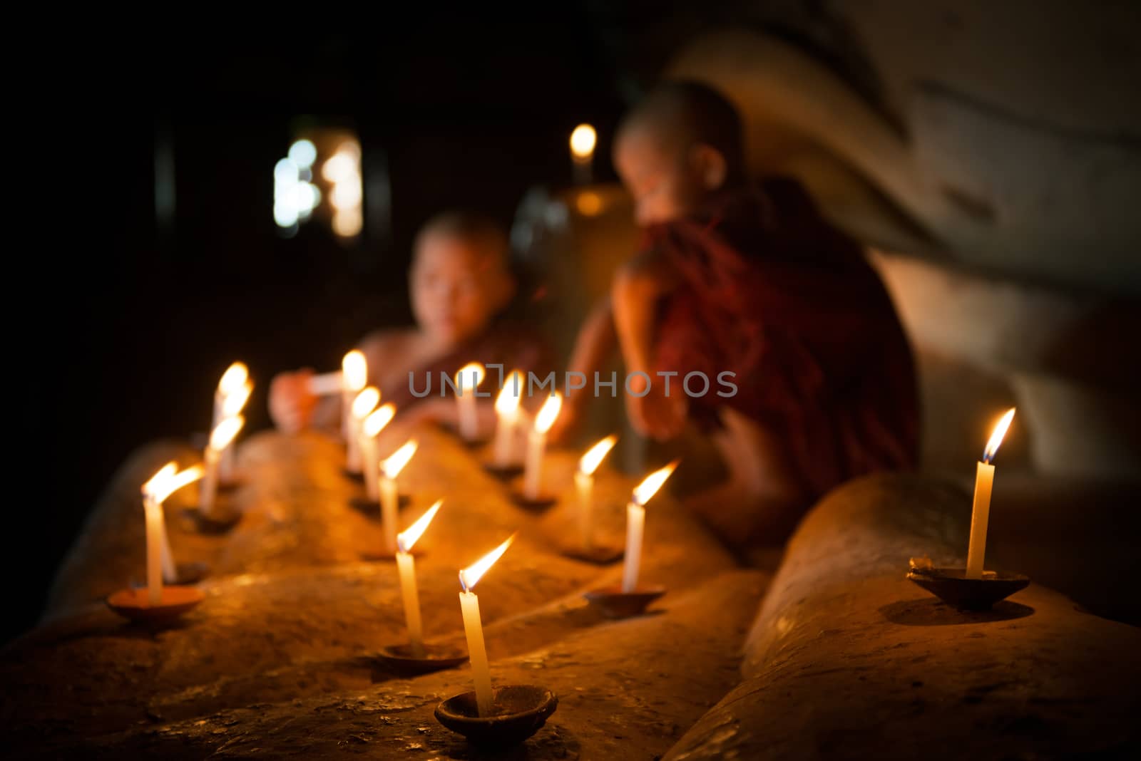 Buddhist novices with candle light inside temple by szefei