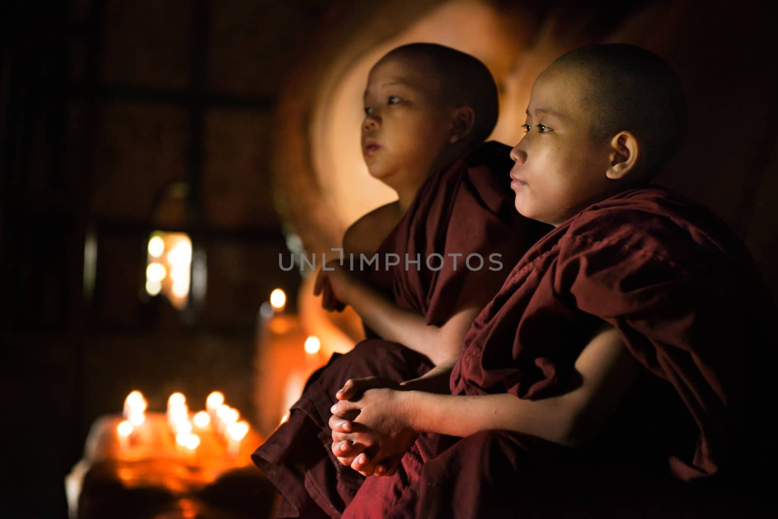 Young novice monks sitting inside a Buddhist temple, Bagan, Myanmar.