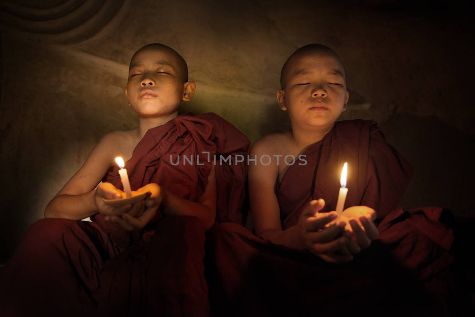 Buddhist novices praying with candlelight by szefei