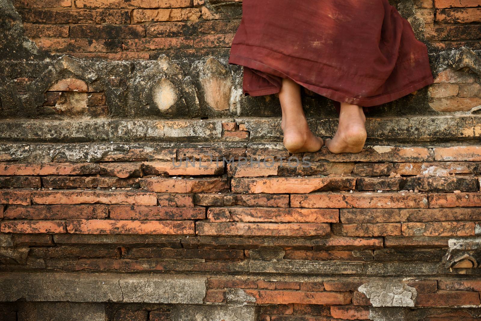 Young novice monk climbing up Buddhist temple, Bagan, Myanmar.