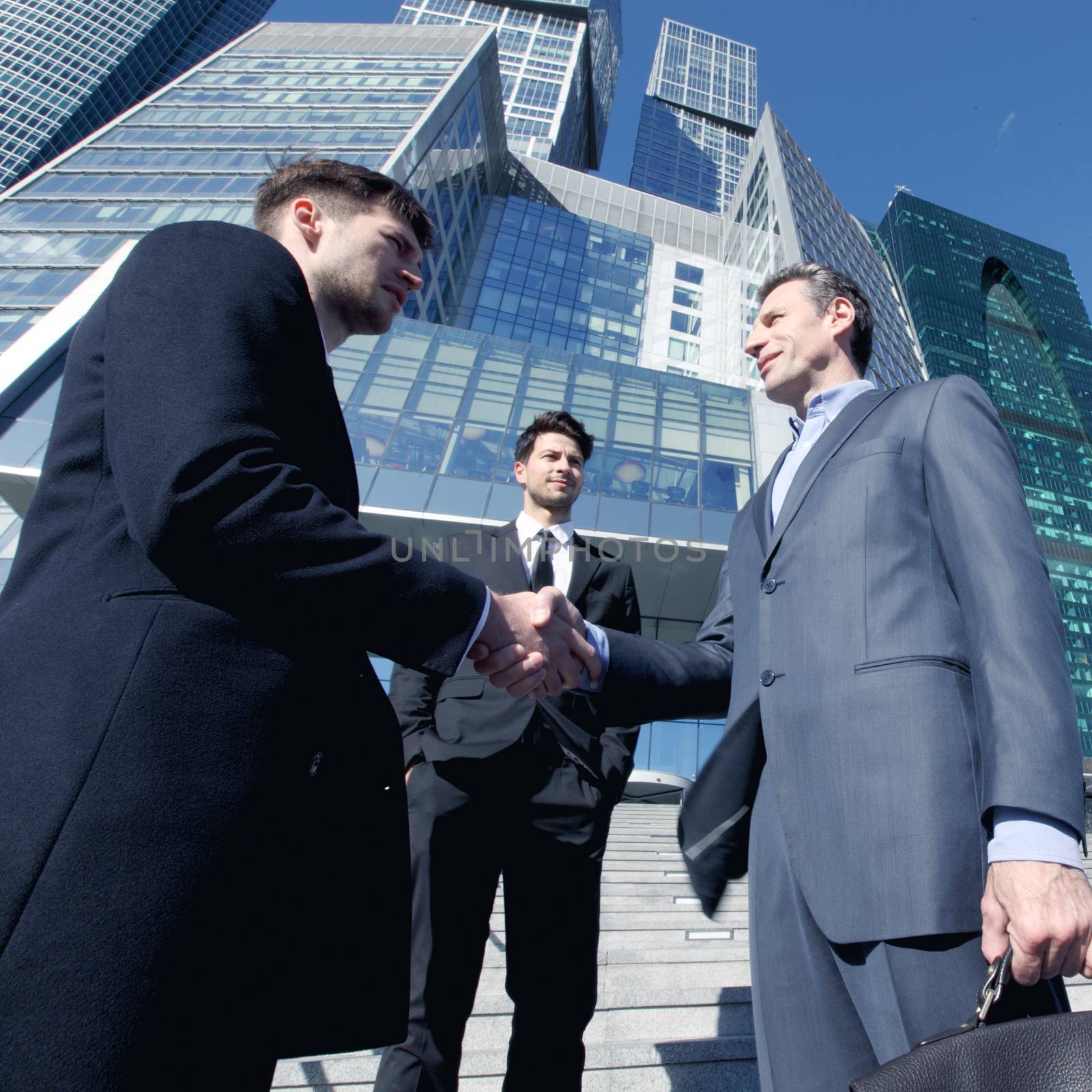 Business people shaking hands, finishing up a meeting outside office