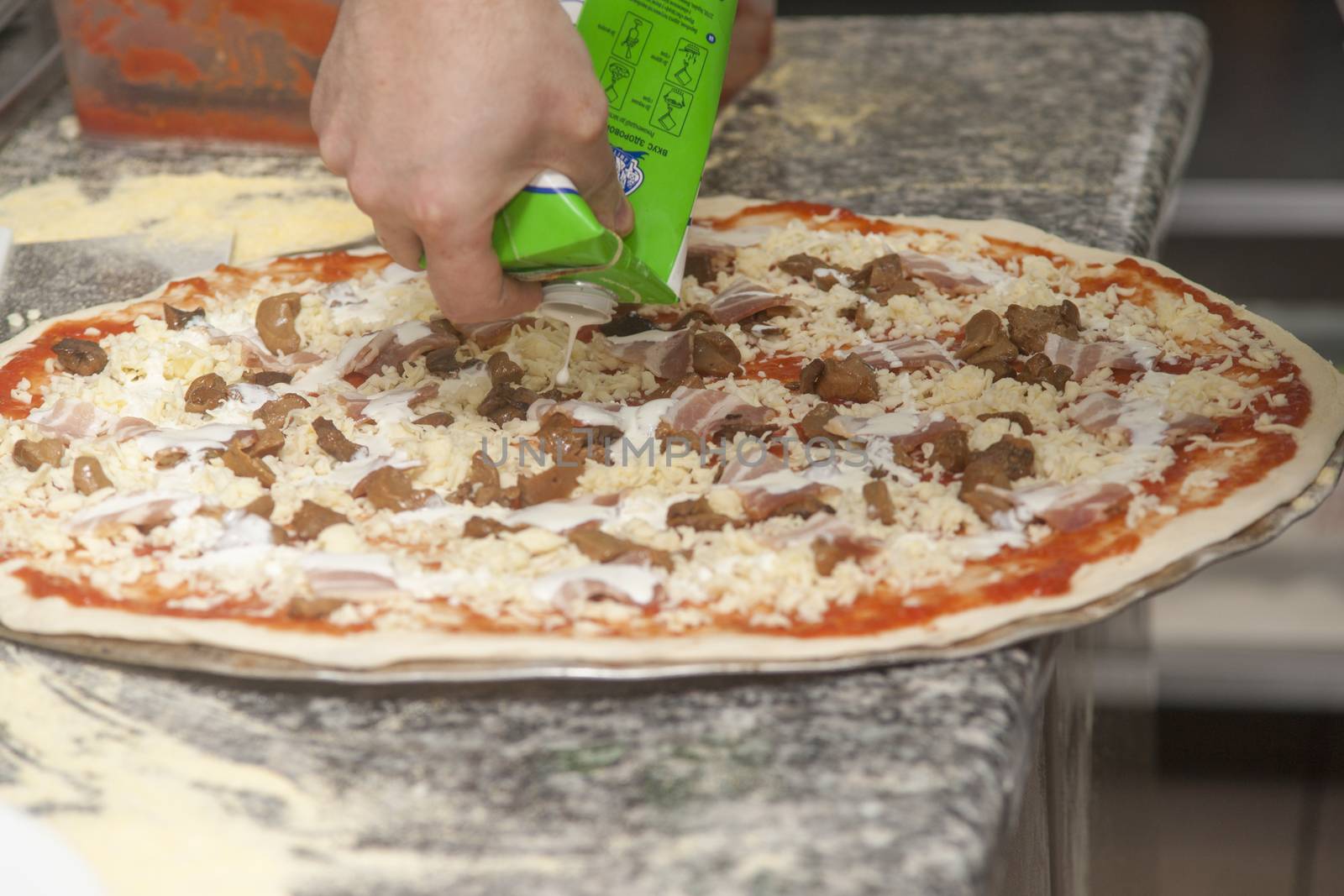 Man chef with raw pizza. Young male in uniform preparing pizza on table.