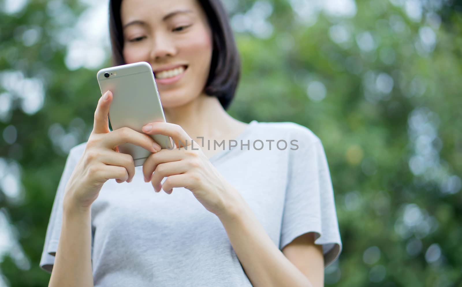 woman using mobile smart phone in the park by ekachailo