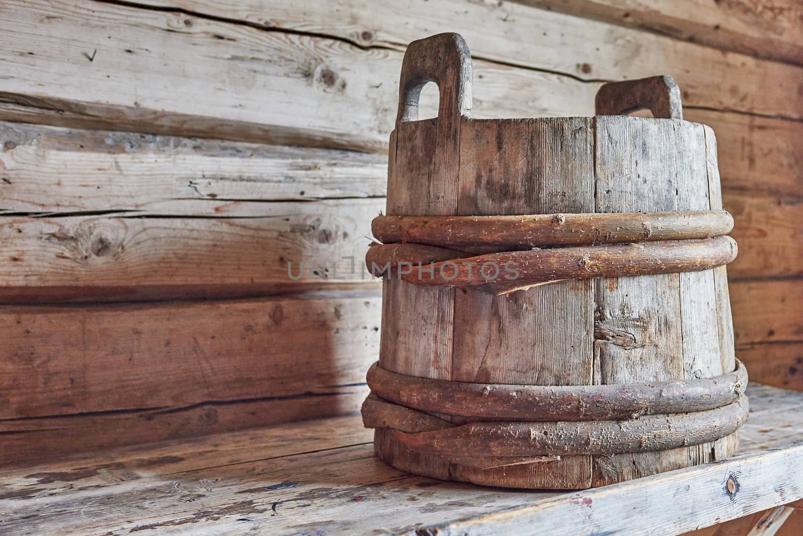 Old wooden bucket on a wooden shelf.