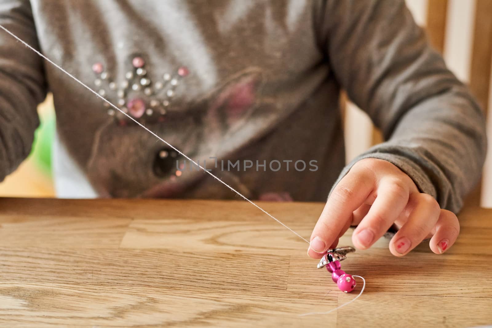 Child playing with beads and a string. Closeup on hands.