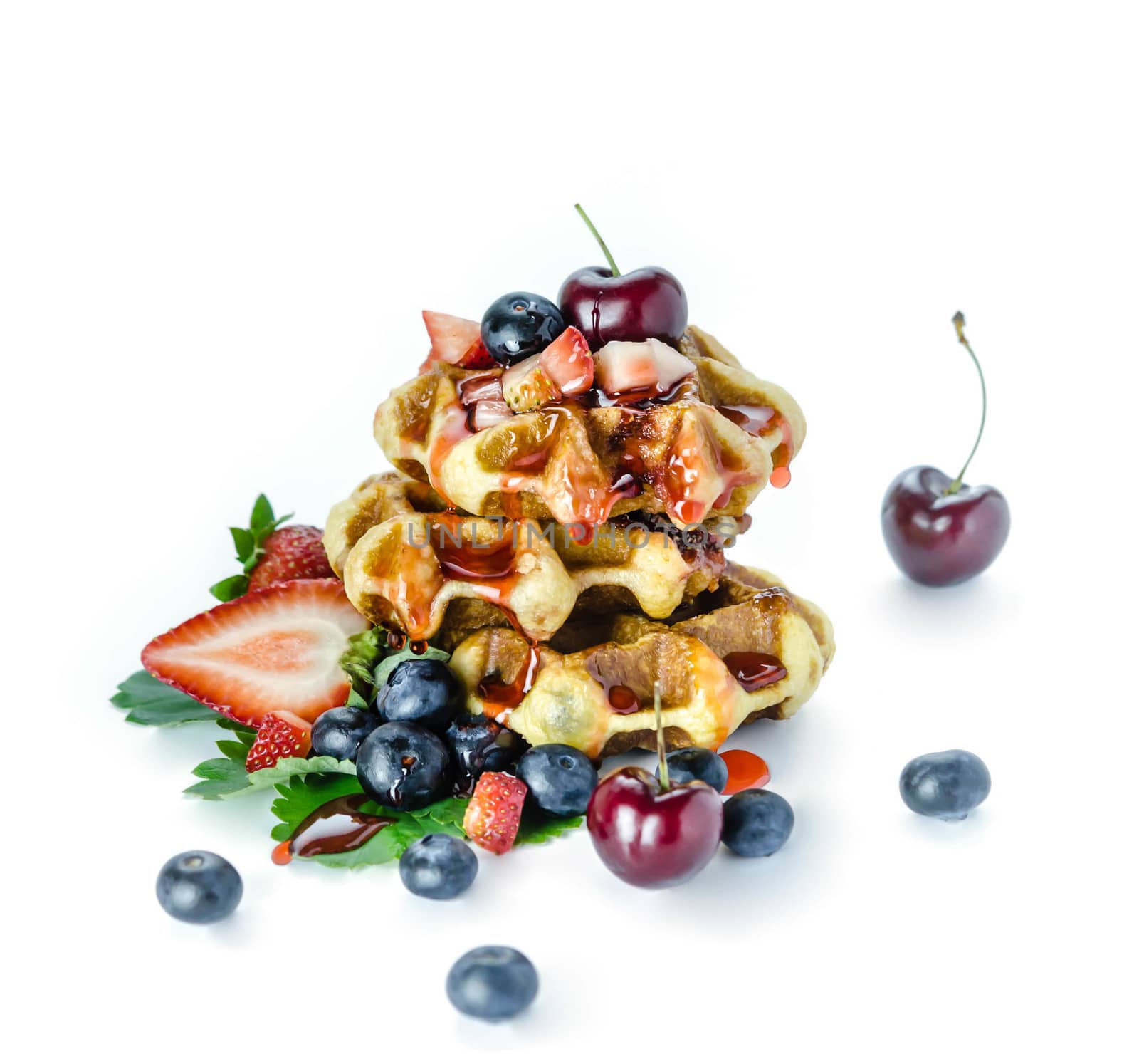 Homemade waffles with strawberry sauce and fresh berries on white background