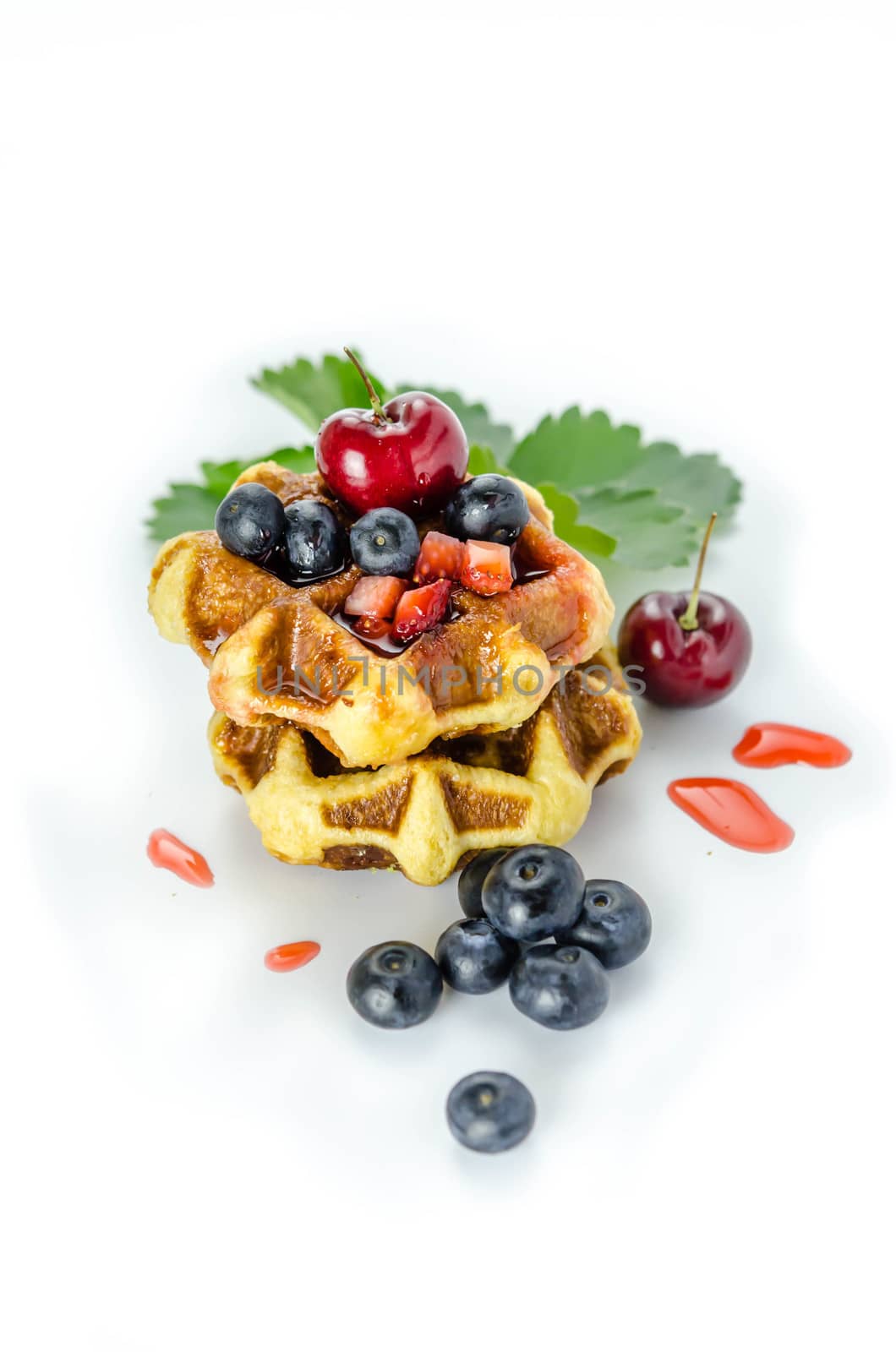 Homemade waffles with strawberry sauce and fresh berries on white background