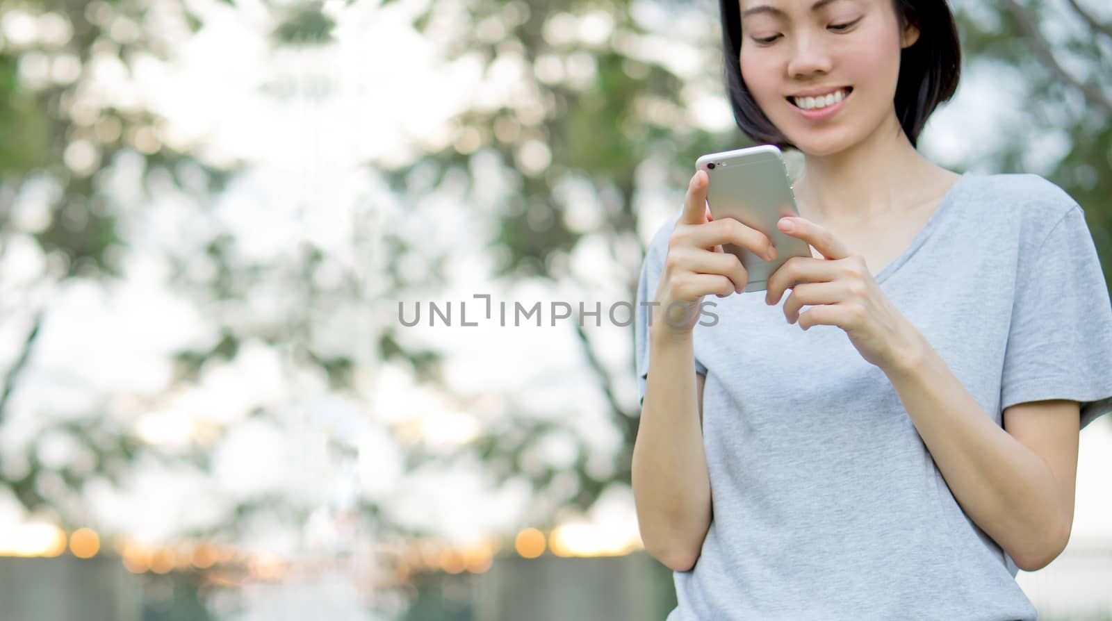 woman using mobile smart phone in the park by ekachailo