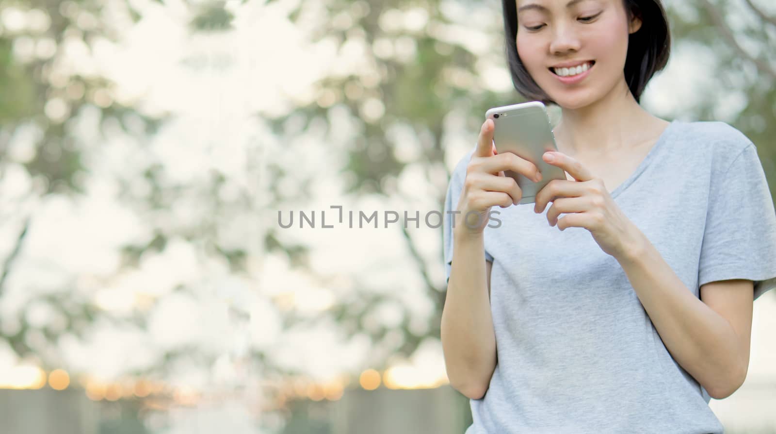 woman using mobile smart phone in the park by ekachailo