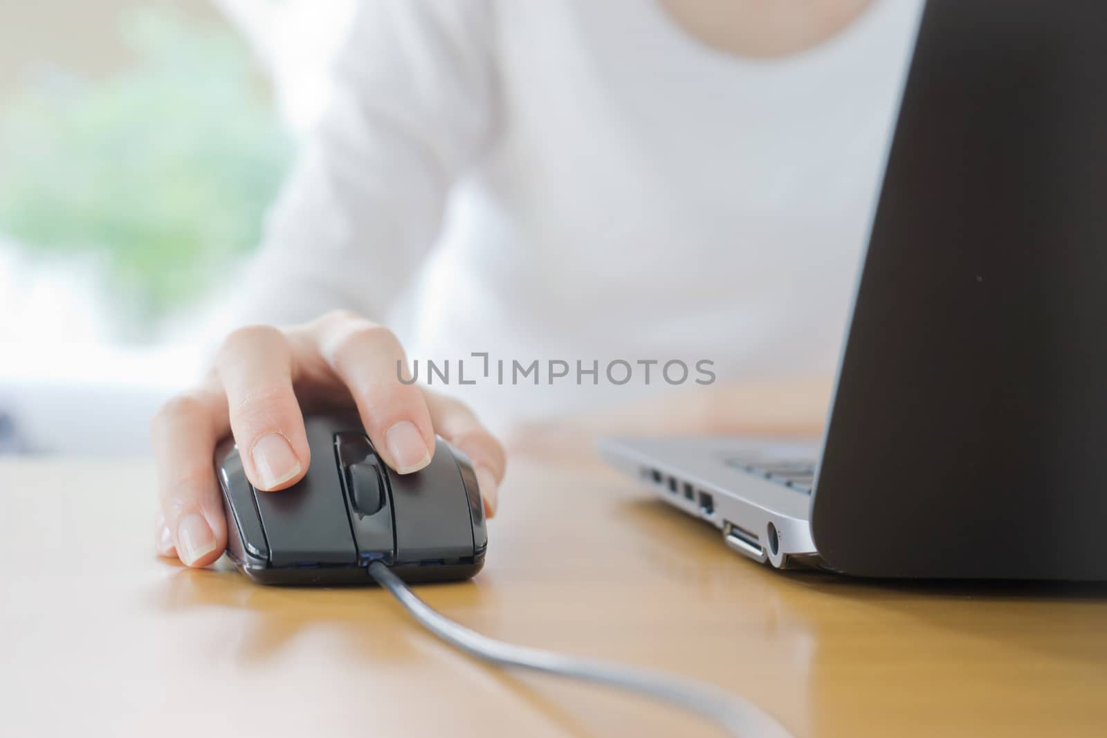 Female hand with computer mouse on table, closeup