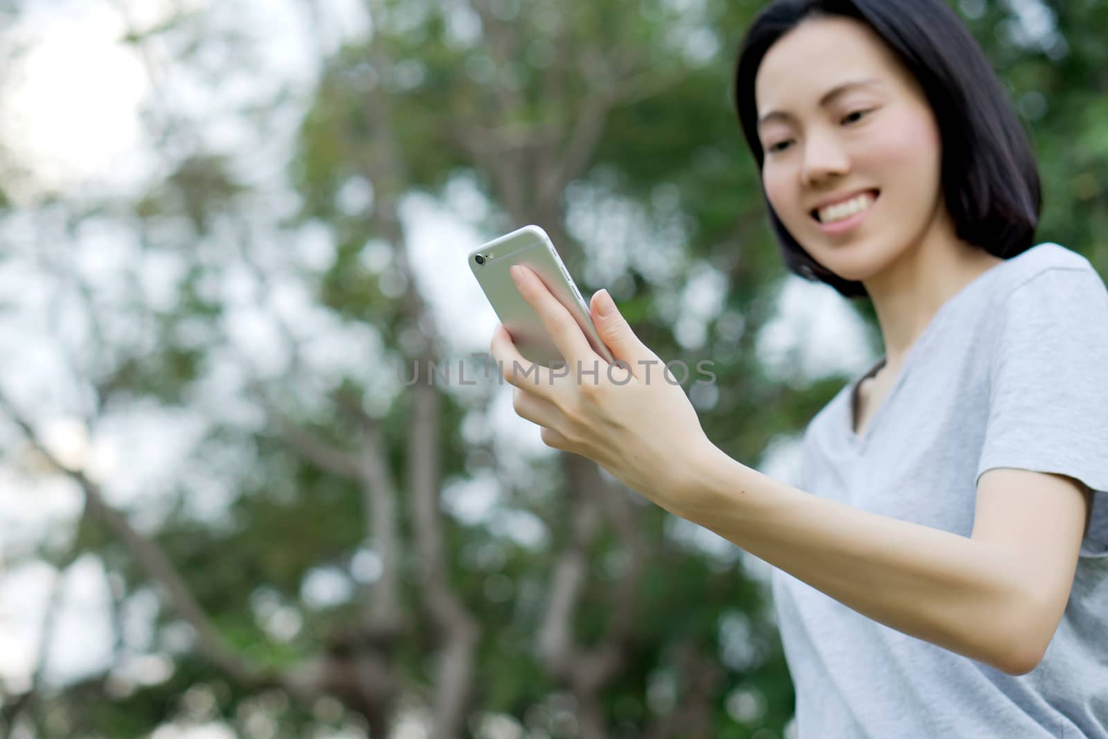 woman using mobile smart phone in the park by ekachailo