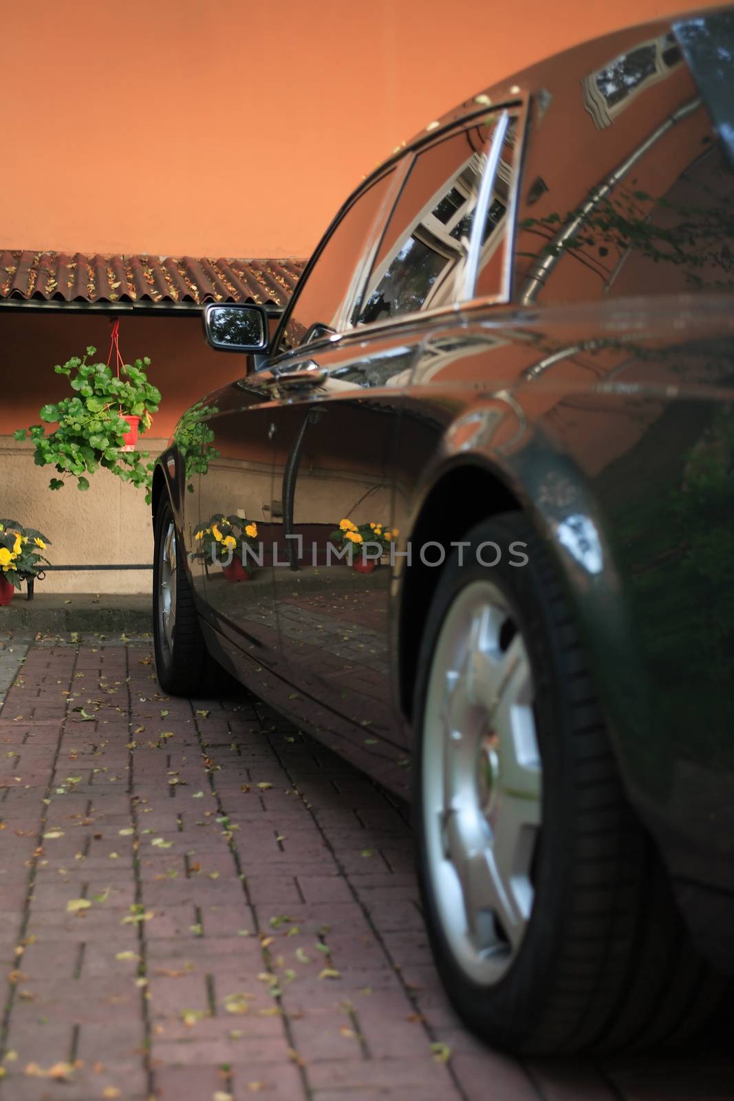 Modern black limousine parking in courtyard near wall