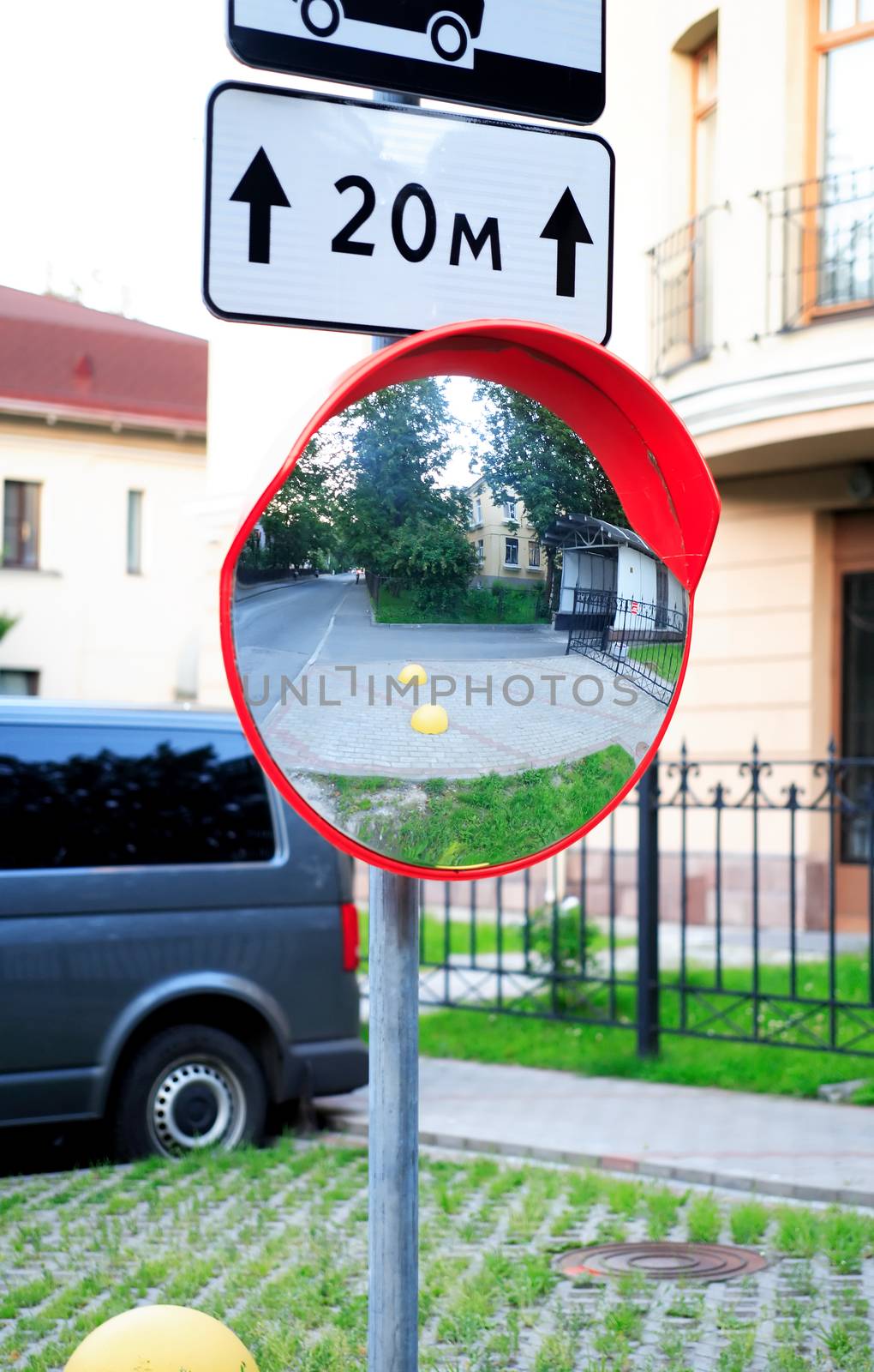 Urban scene. Closeup of metal pole with road sign and big circle mirror